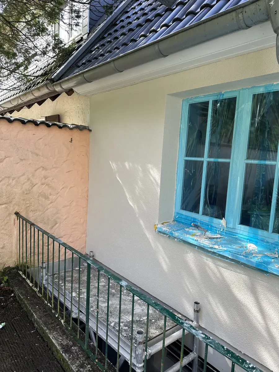 Neu verputzte Altbaufassade mit abgeklebtem Fenster und Kellerabgang