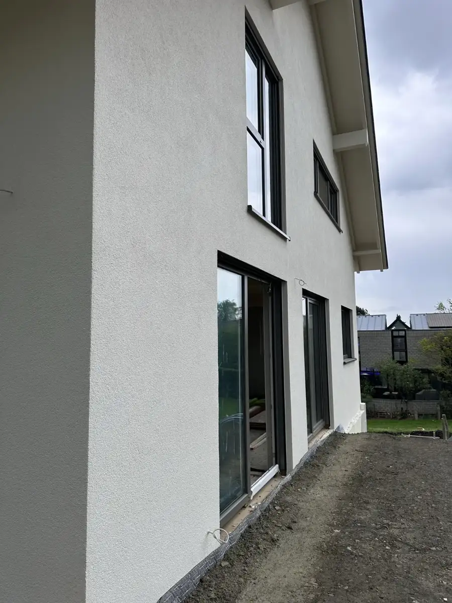 Weiß verputzte Hauswand eines Einfamilienhauses mit Terrassentüren