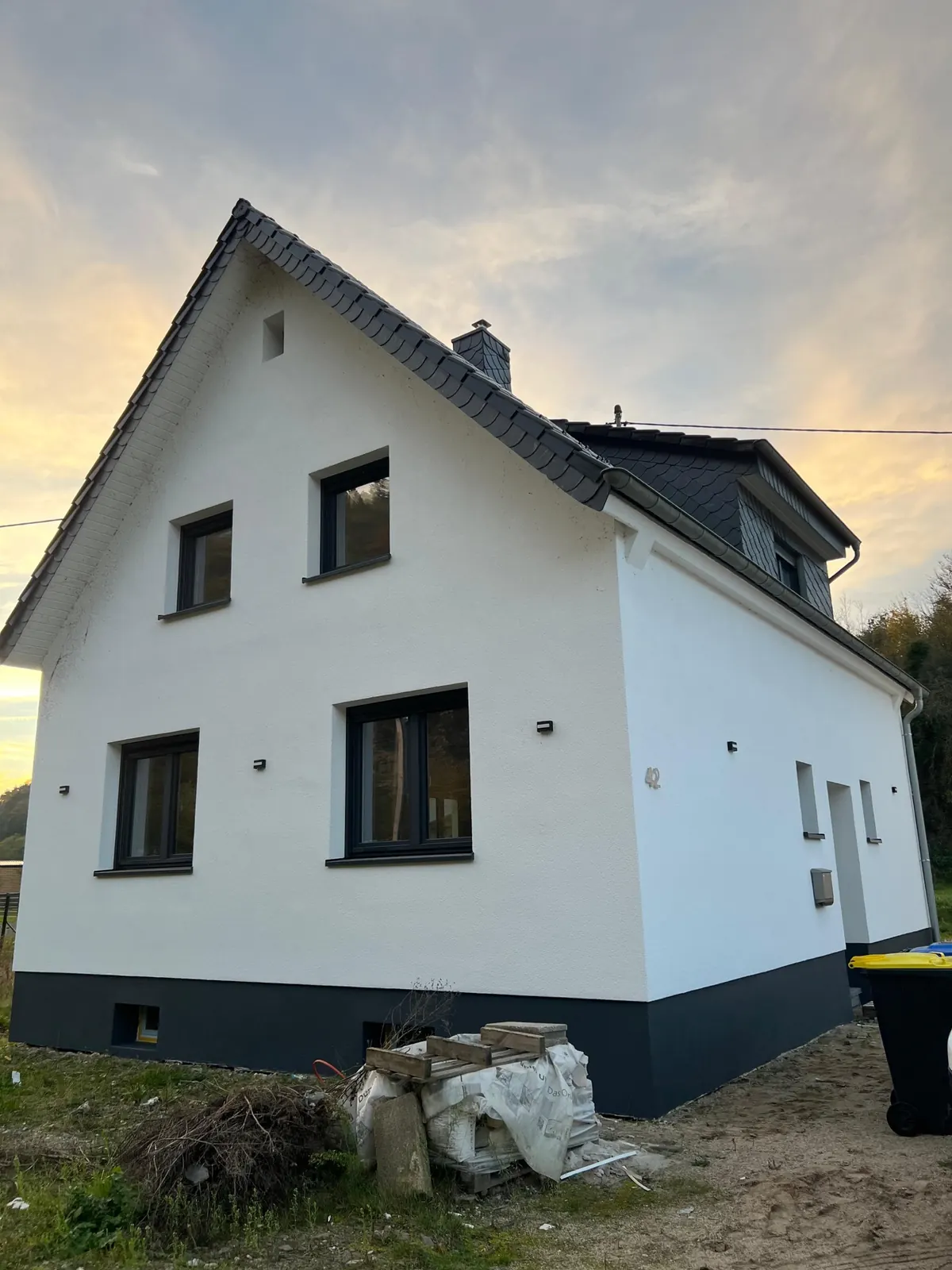 Einfamilienhaus mit neuem weißem Außenputz und dunklem Sockel