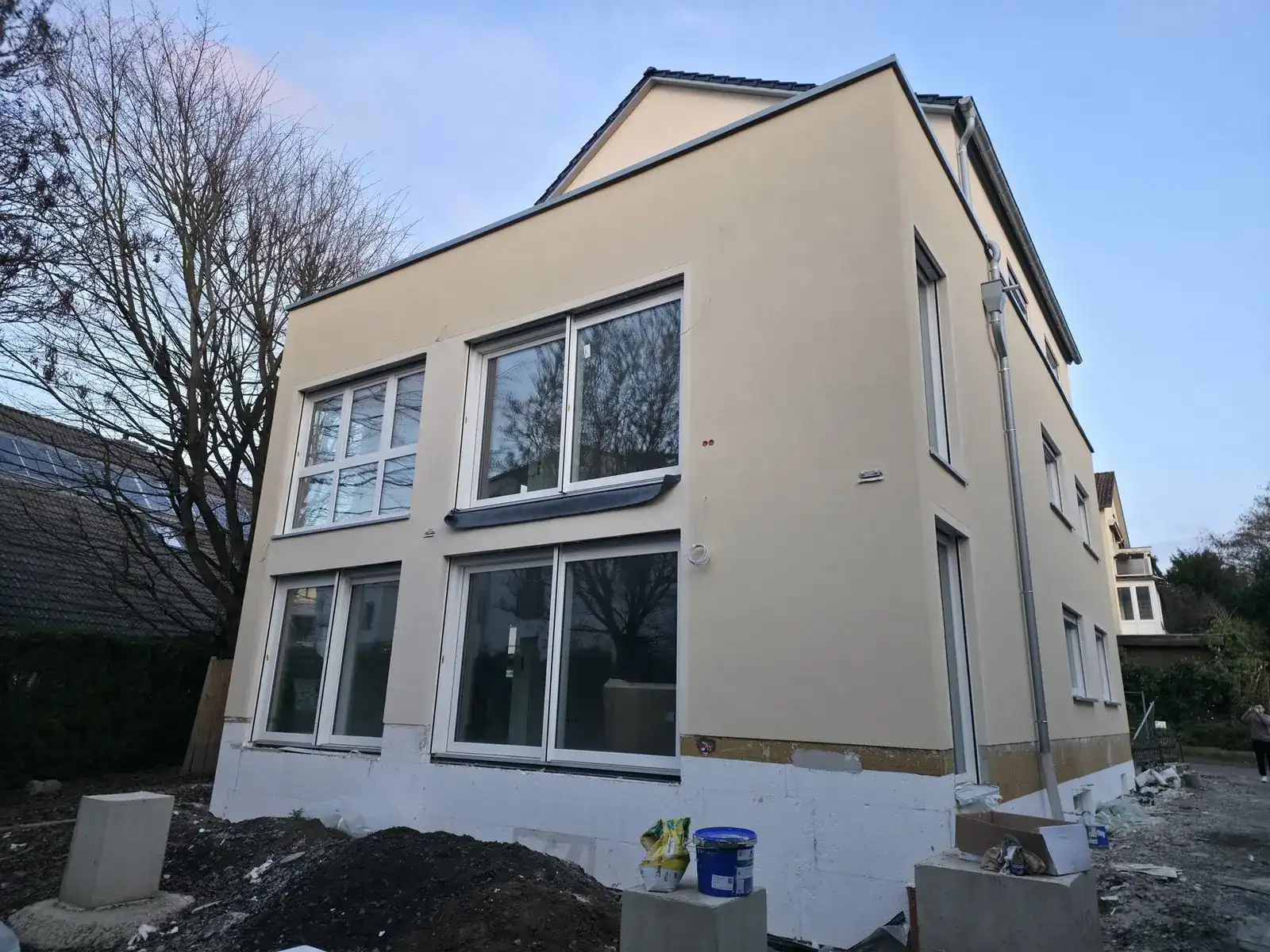 Mehrfamilienhaus mit beigem Außenputz und großen Fensterflächen