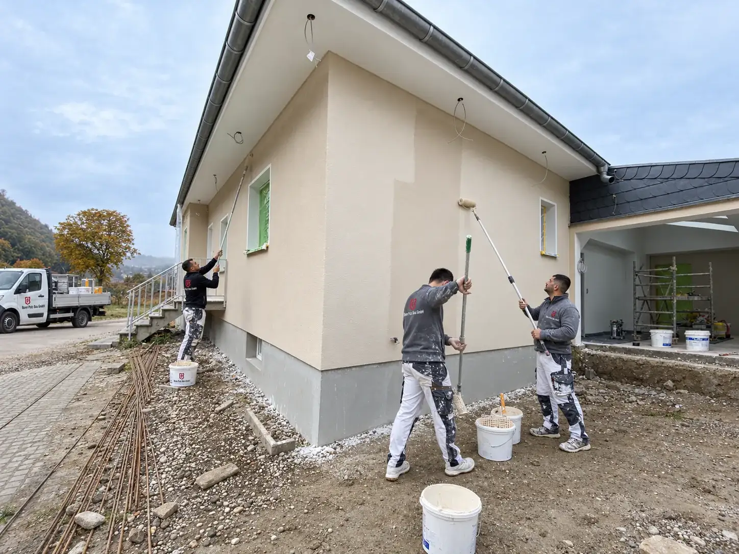 Mitarbeiter von Bonn Putz Bau grundieren die verputzte Fassade eines Bungalows