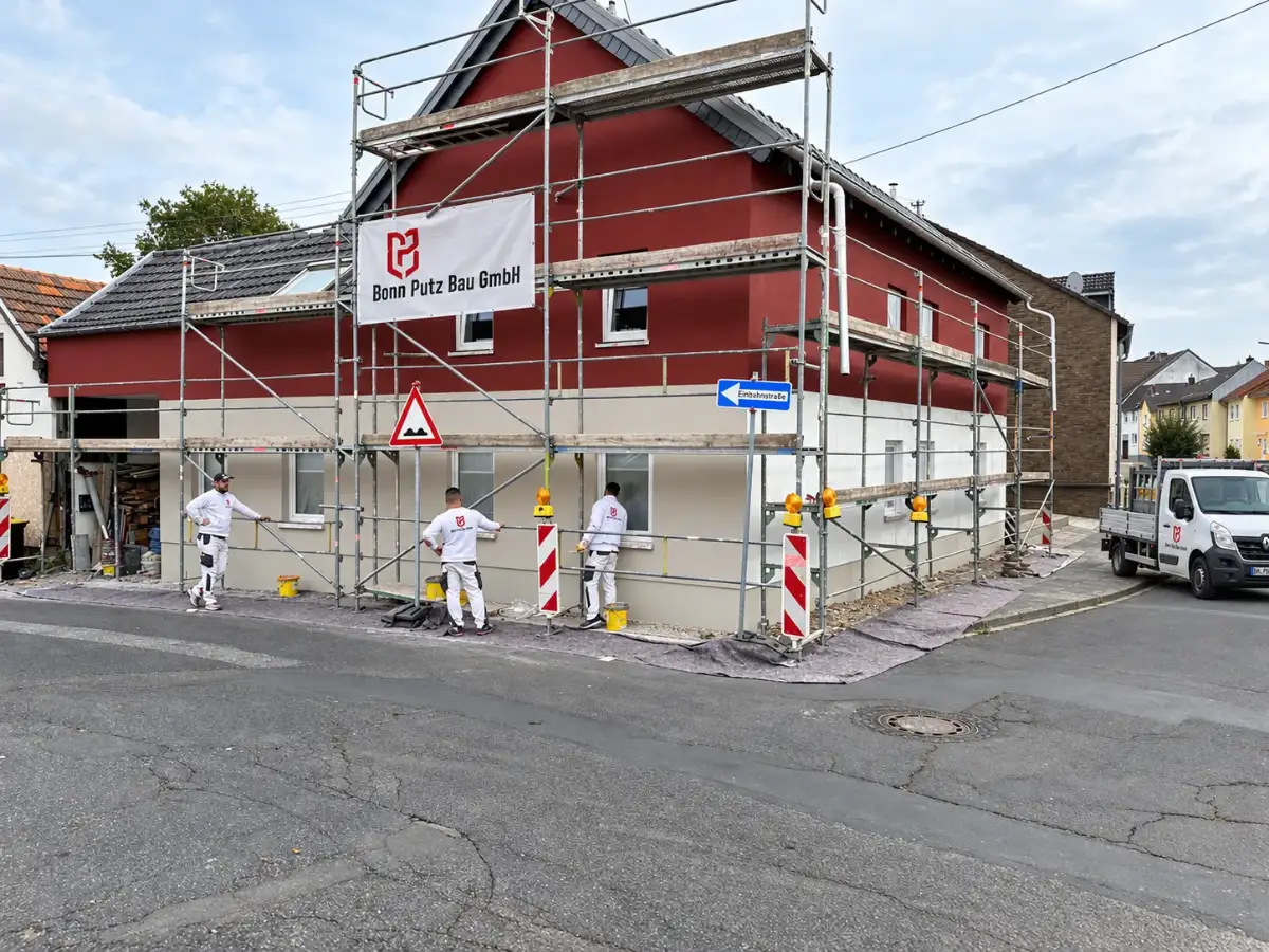 Eingerüstetes Wohnhaus mit Banner von Bonn Putz Bau während der Fassadensanierung