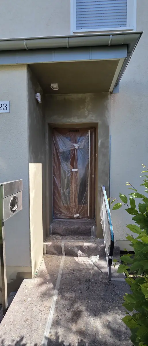 Hauseingang mit grauem Altputz vor der Sanierung