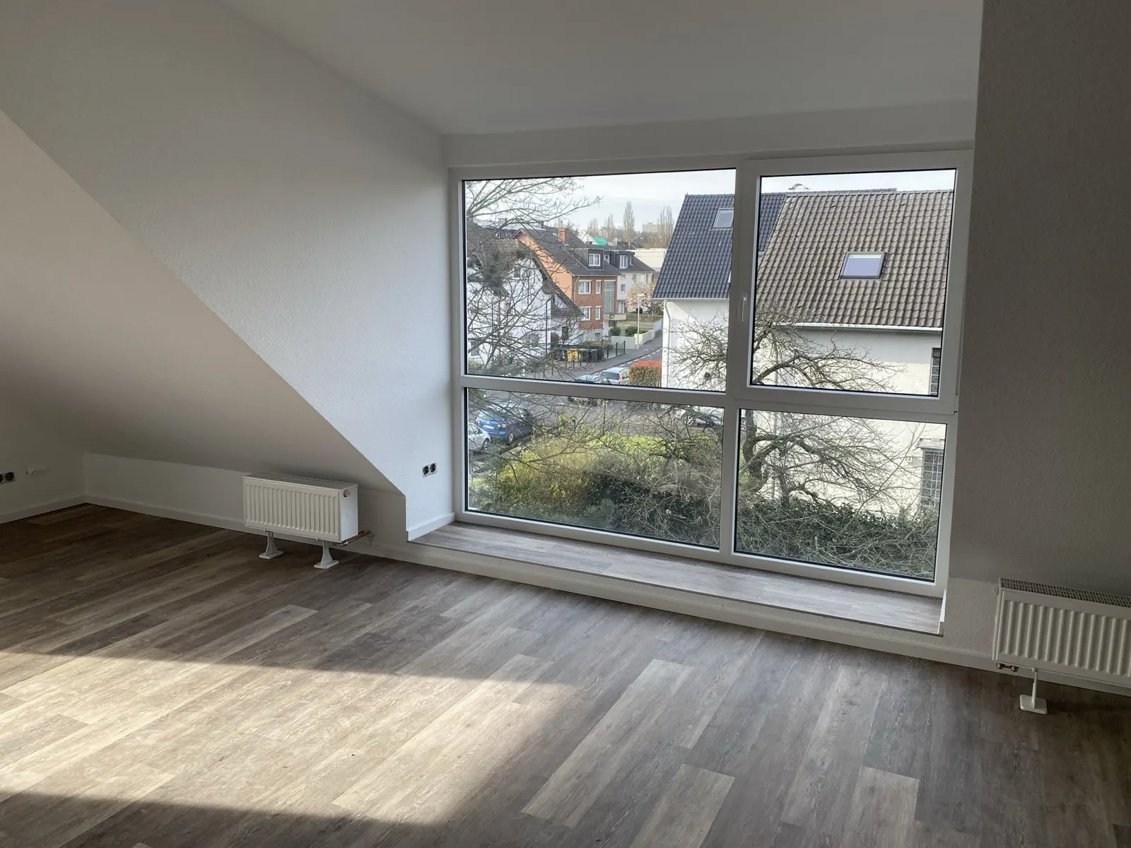 Dachgeschosszimmer mit großem Fenster und neuem Boden