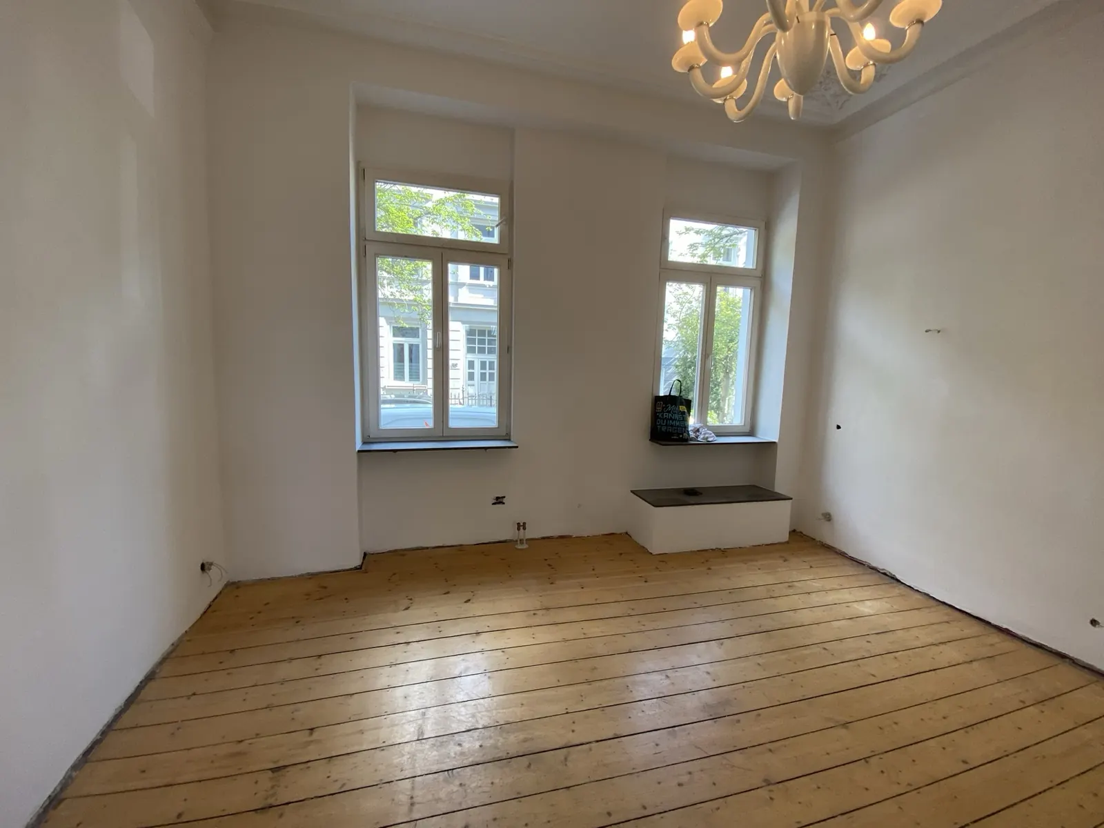 Renoviertes Altbauzimmer mit Dielenboden und hohen Fenstern