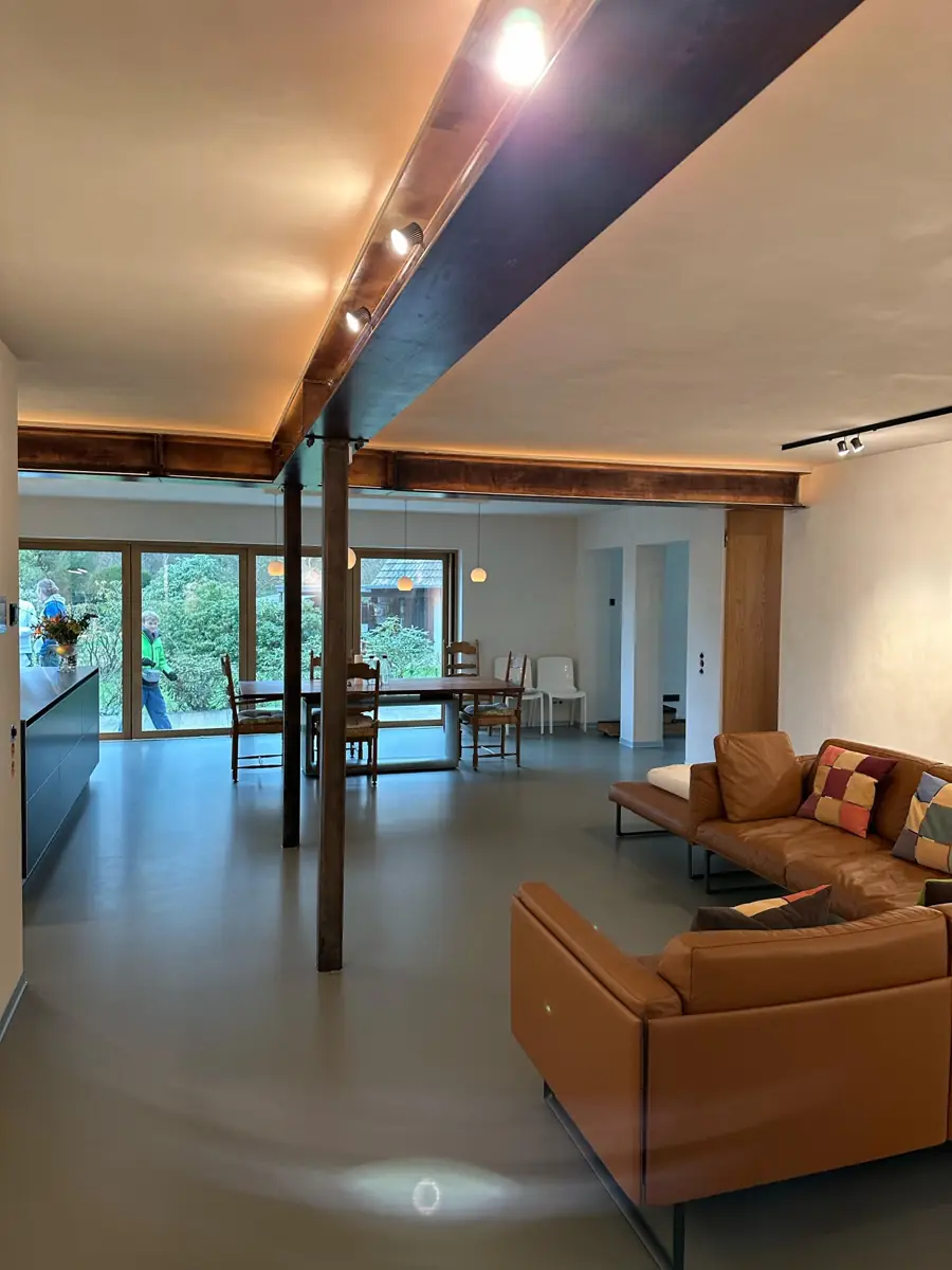 Großer sanierter Wohnraum mit Holz-Stahl-Balken, Lichtvouten und grauem Boden