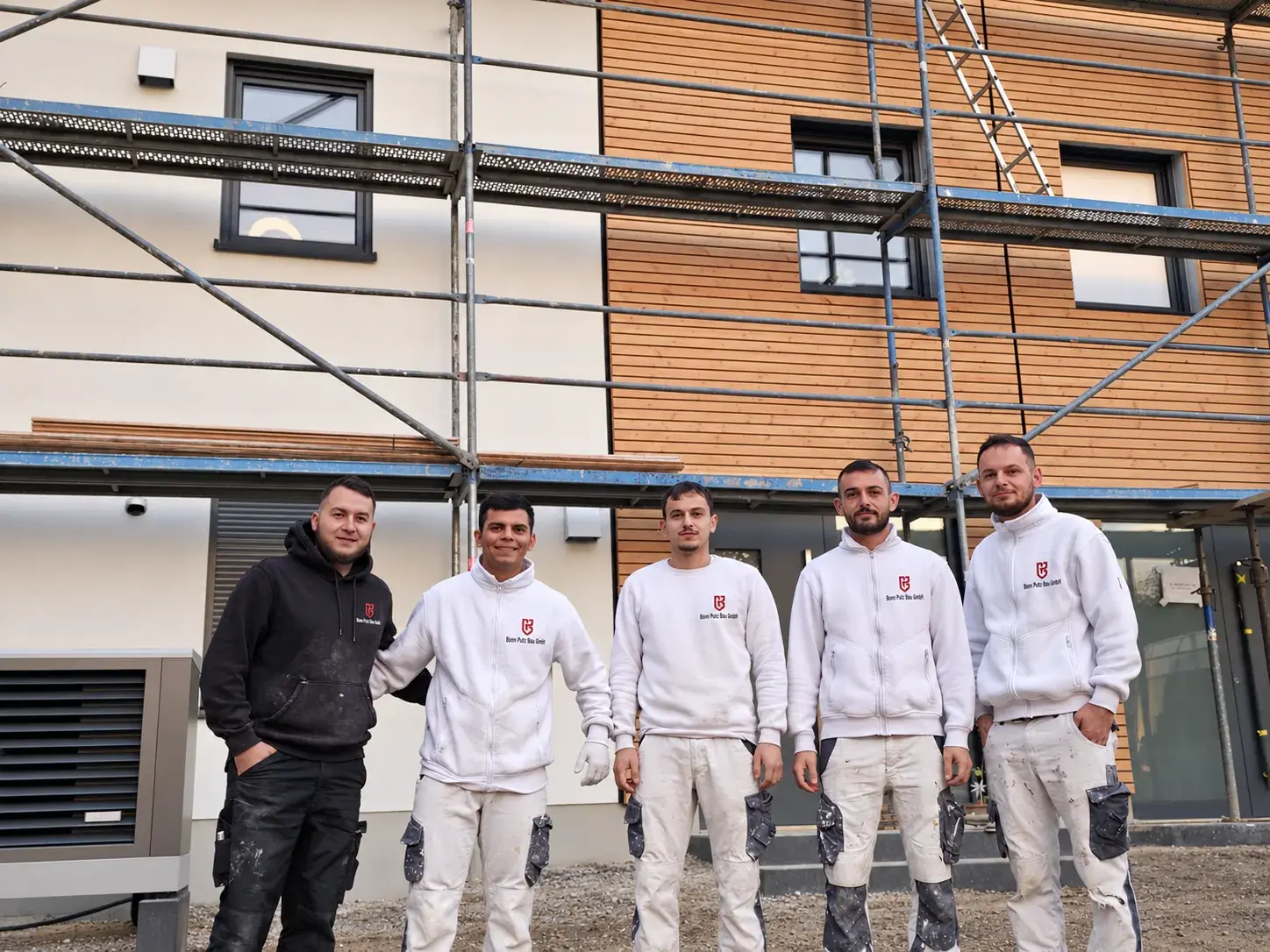 Team von Bonn Putz Bau vor einem Neubau mit Holzfassade